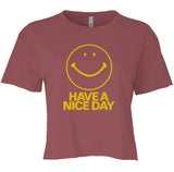 A short-sleeve crewneck t-shirt in a dusty rose or mauve color, featuring a yellow smiley face graphic and the text 'HAVE A NICE DAY' printed on the front.