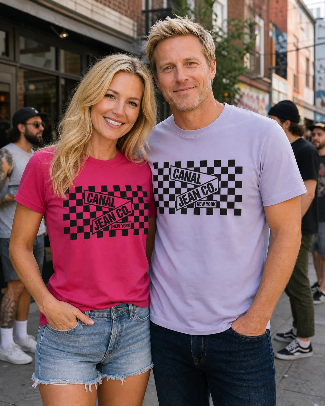 A man and a woman standing together on a city street, both wearing Vans 'Jeans Co.' t-shirts.