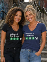 Two women standing on outdoor concrete stairs wearing matching graphic V-neck t-shirts. The shirt on the left is black with white text reading 'Uptown & The Bronx' above green circles with white numbers '4 5 6' and a white arrow.
