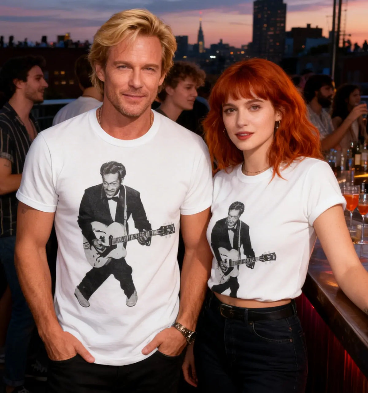 Two people wearing t-shirts with guitarists' images at a rooftop bar with a cityscape background.
