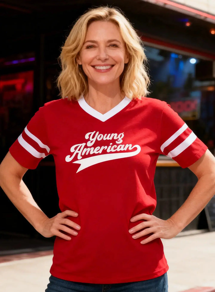 Woman wearing a red 'Young American' shirt standing in front of a bar.